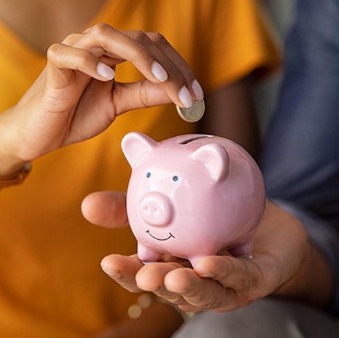 a person putting a coin into a piggy bank